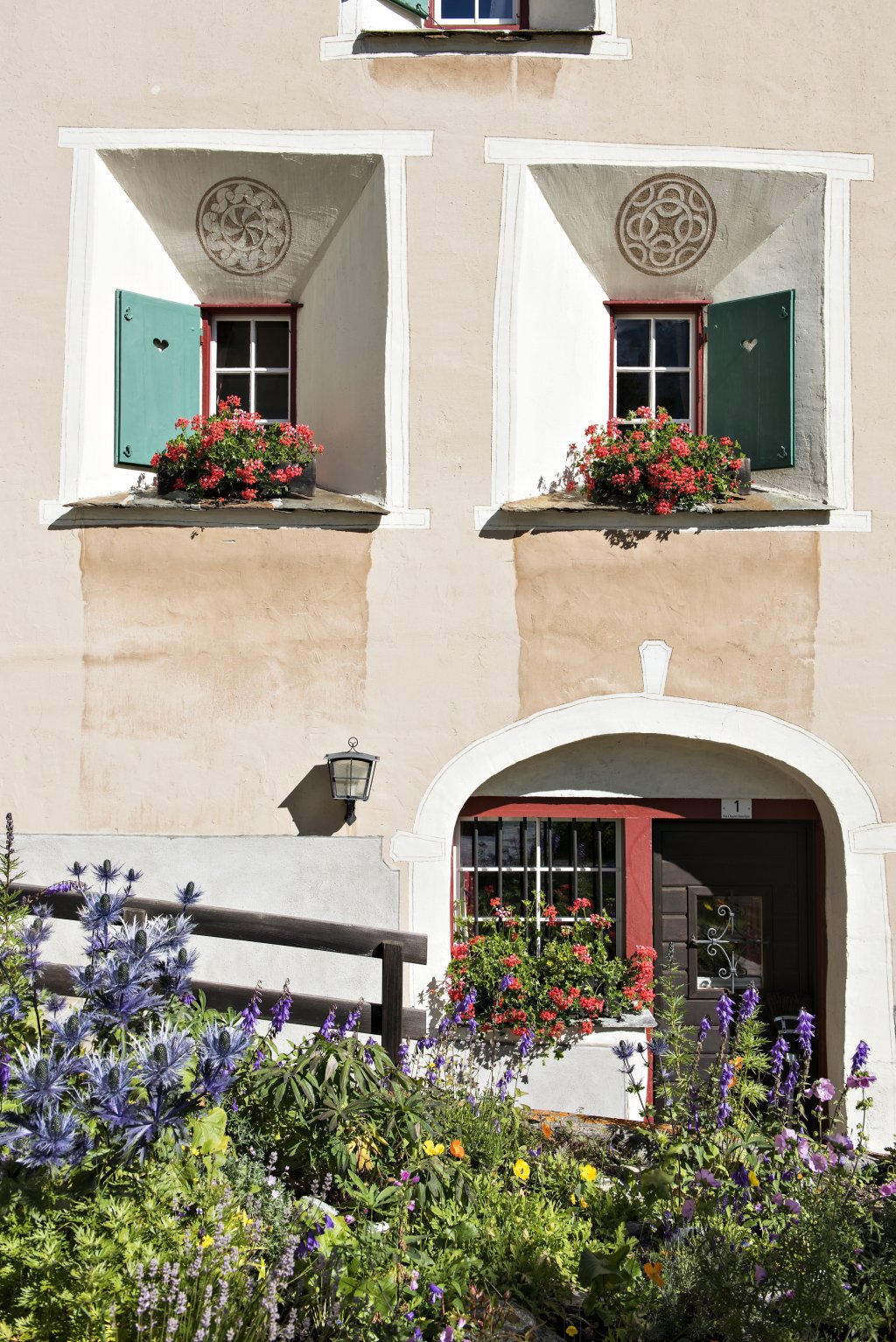 Engadinerhaus mit Sgrafito und Blumen.